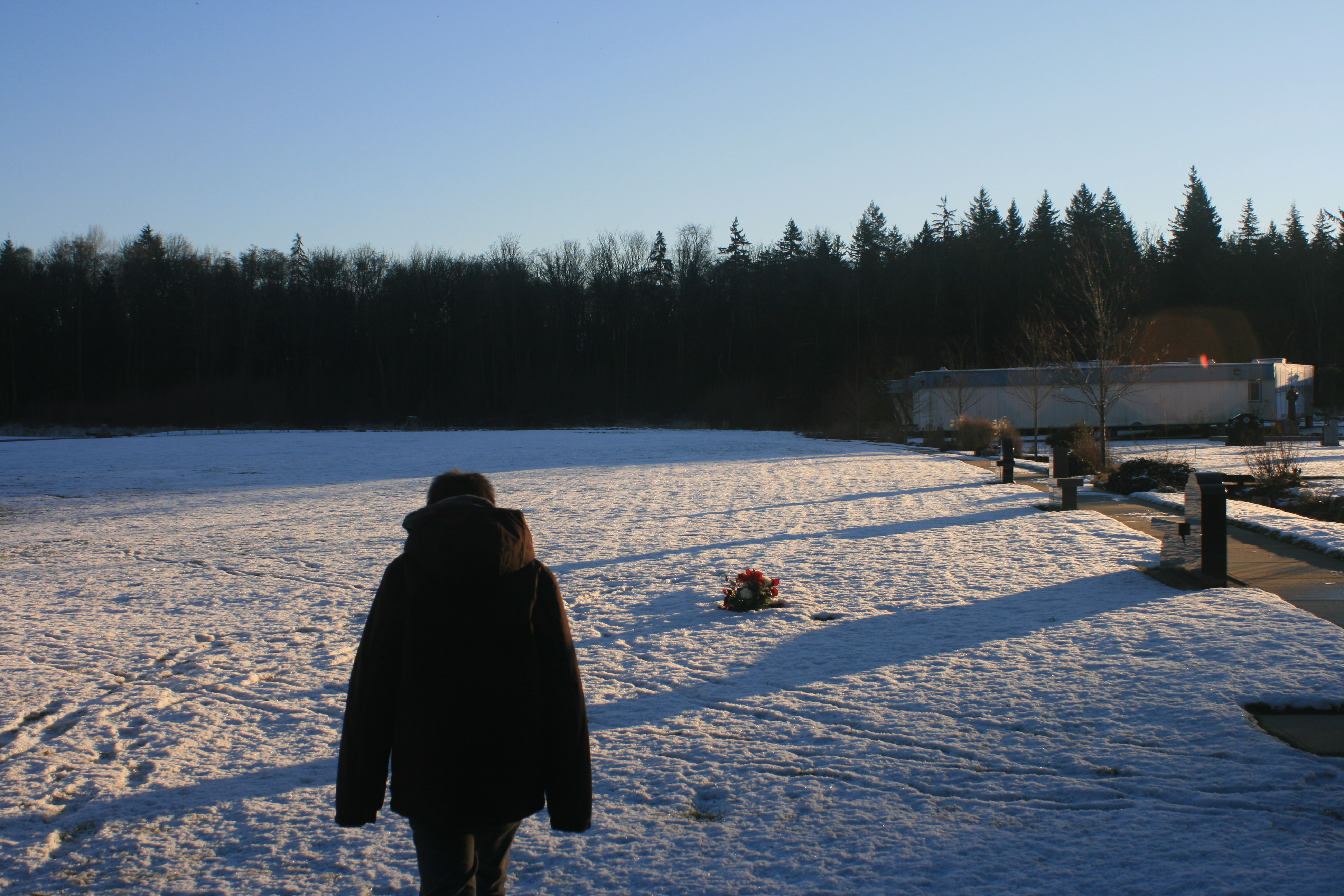 a person walks through a cemetary on a snowy, sunny day