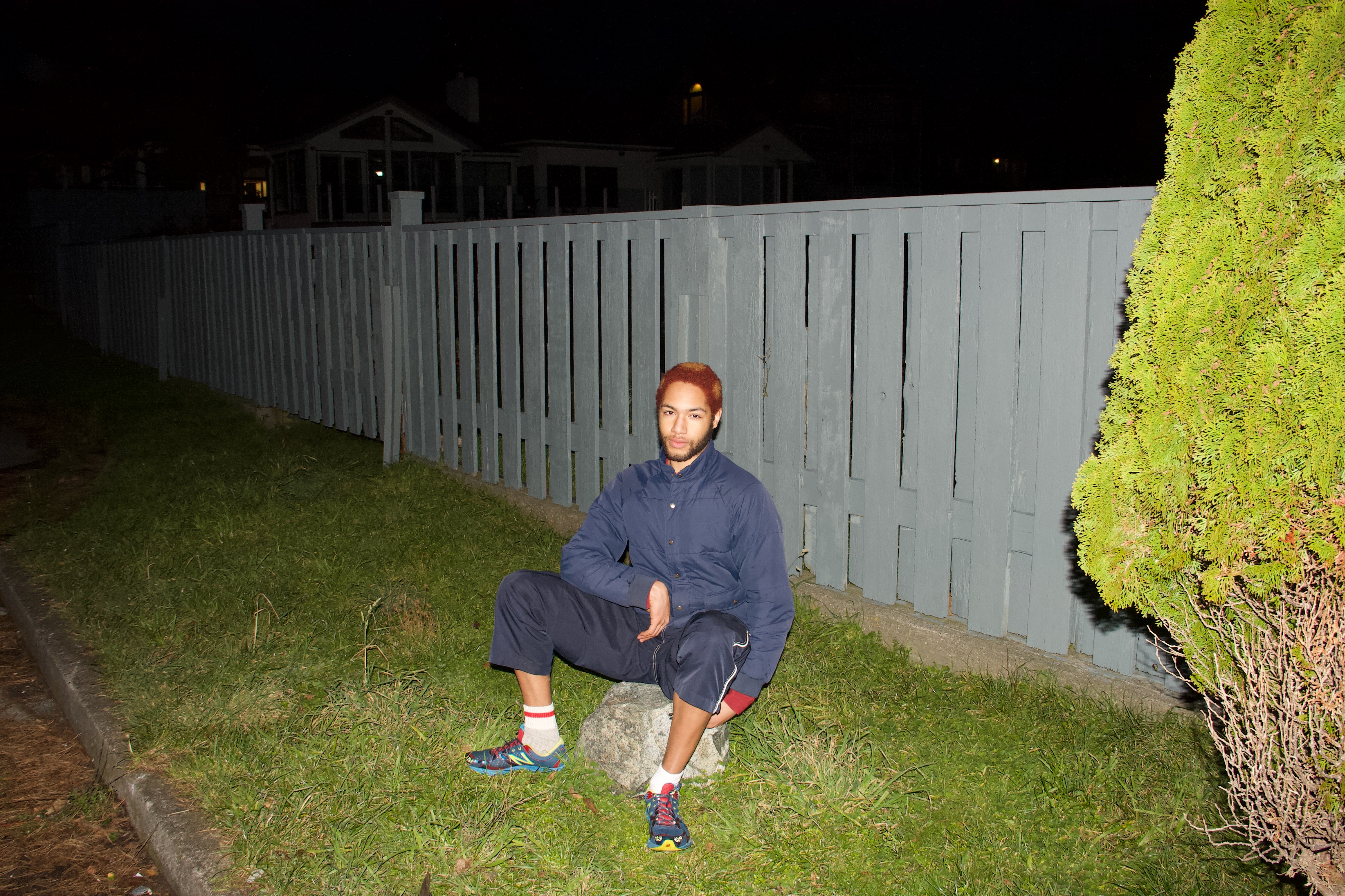 dorone at night, sitting in front of a fence