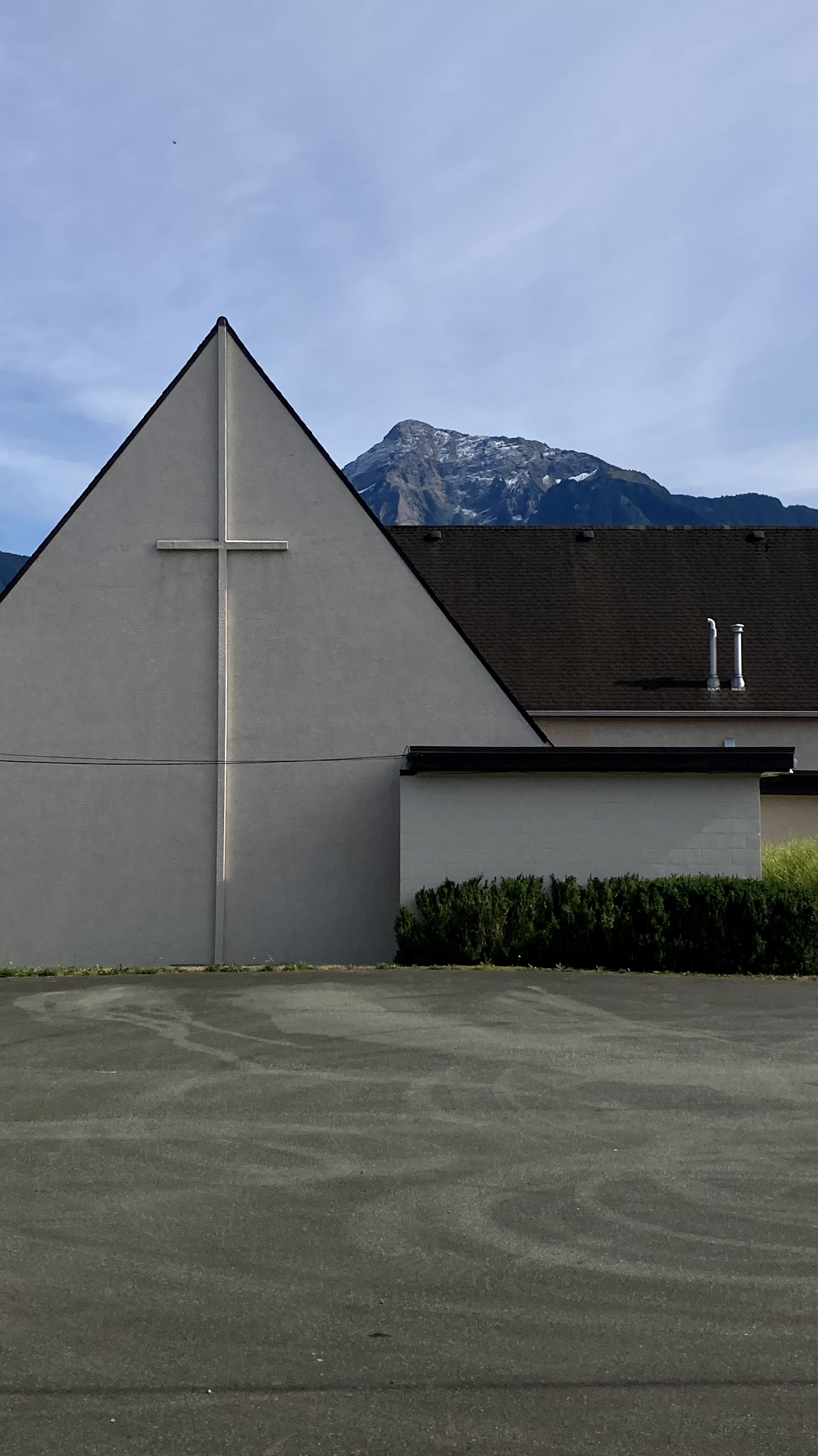 a tall mountain with a small amount of snow peaks over a church in agassiz, british columbia