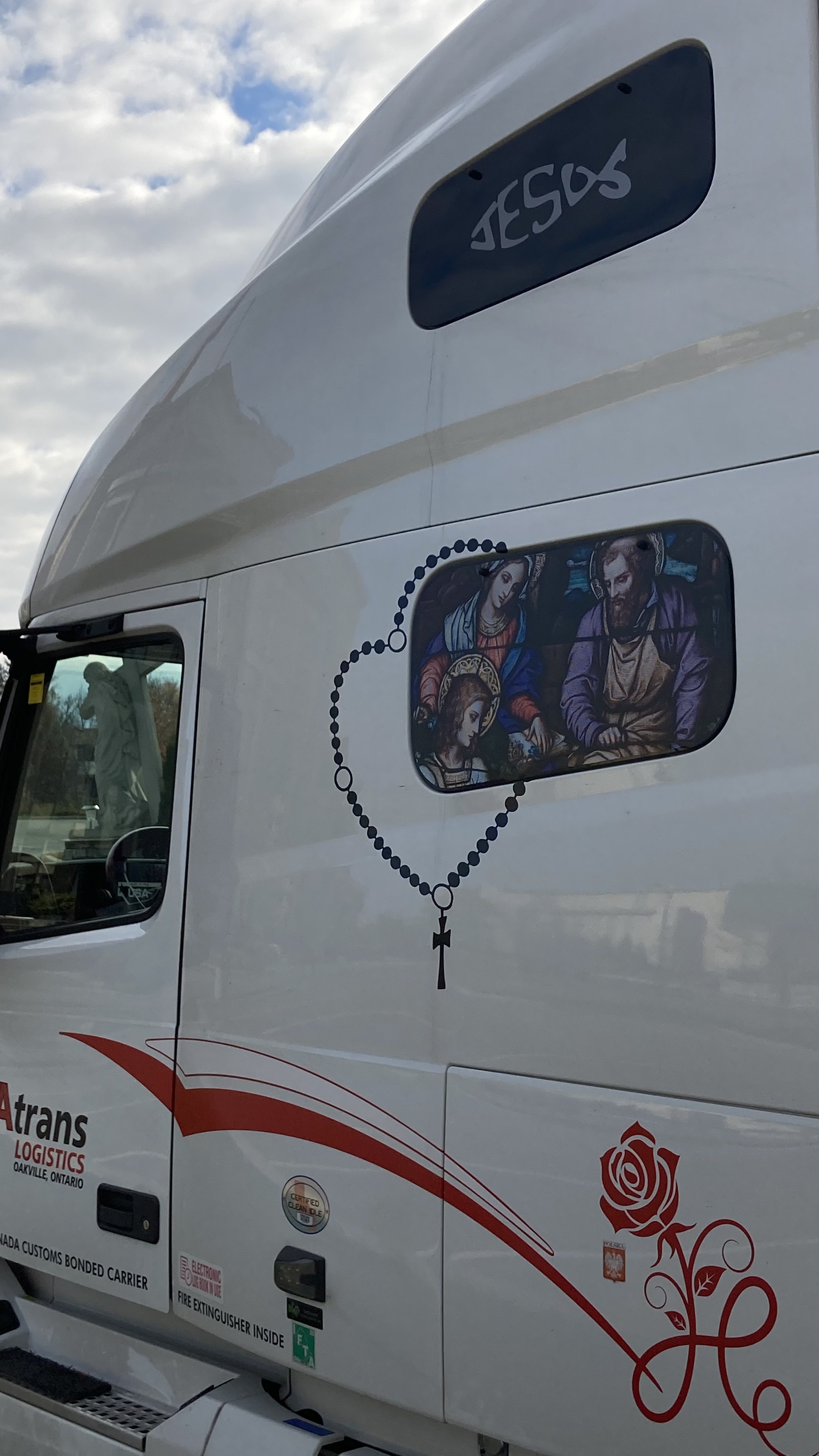 a statue of jesus christ carrying a cross can be seen through the window of a truck emblazoned with decals of jesus christ, brampton, ontario