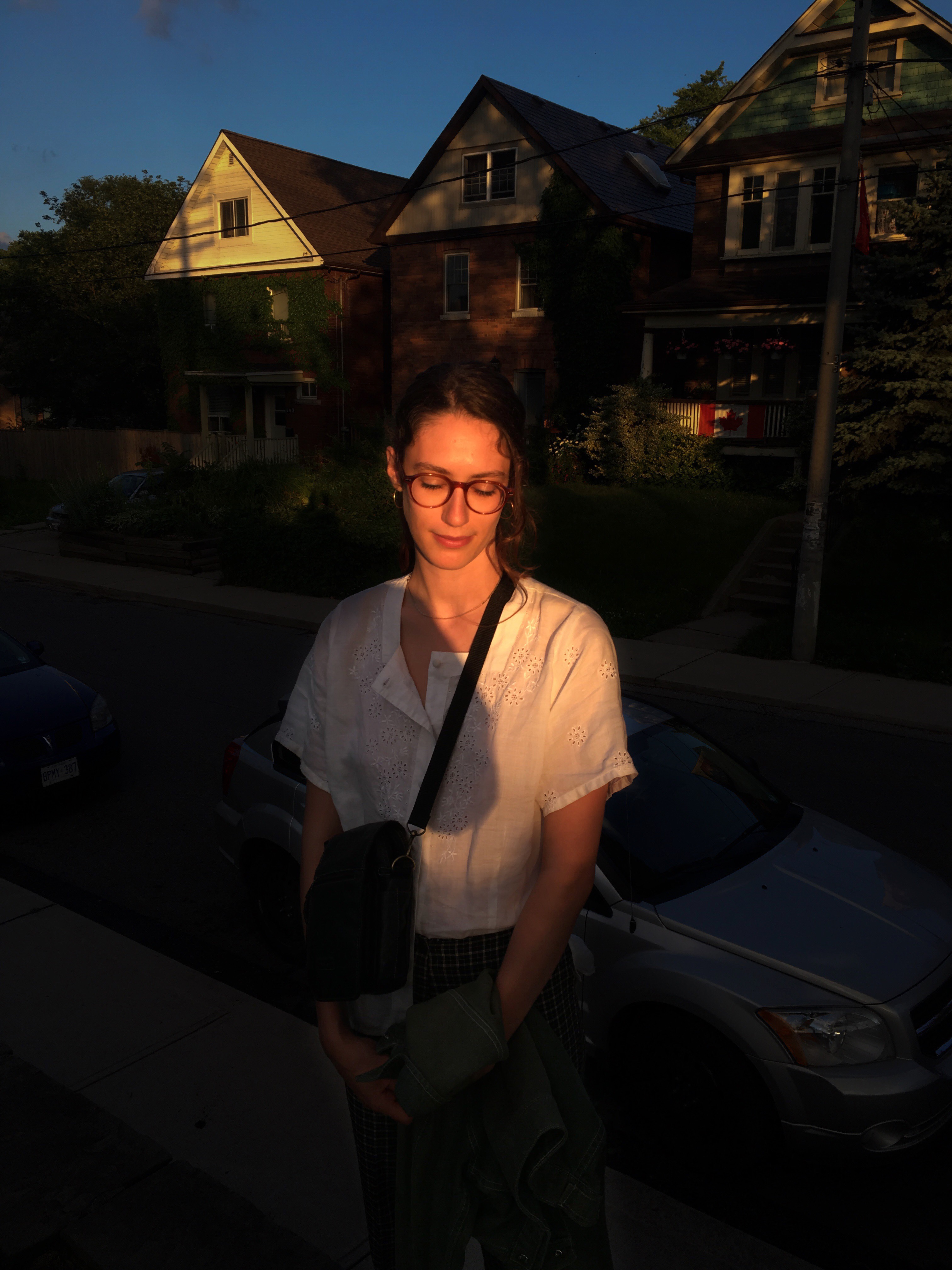 treme stands in sunlight and partial shadows from the photographer, in front of some houses