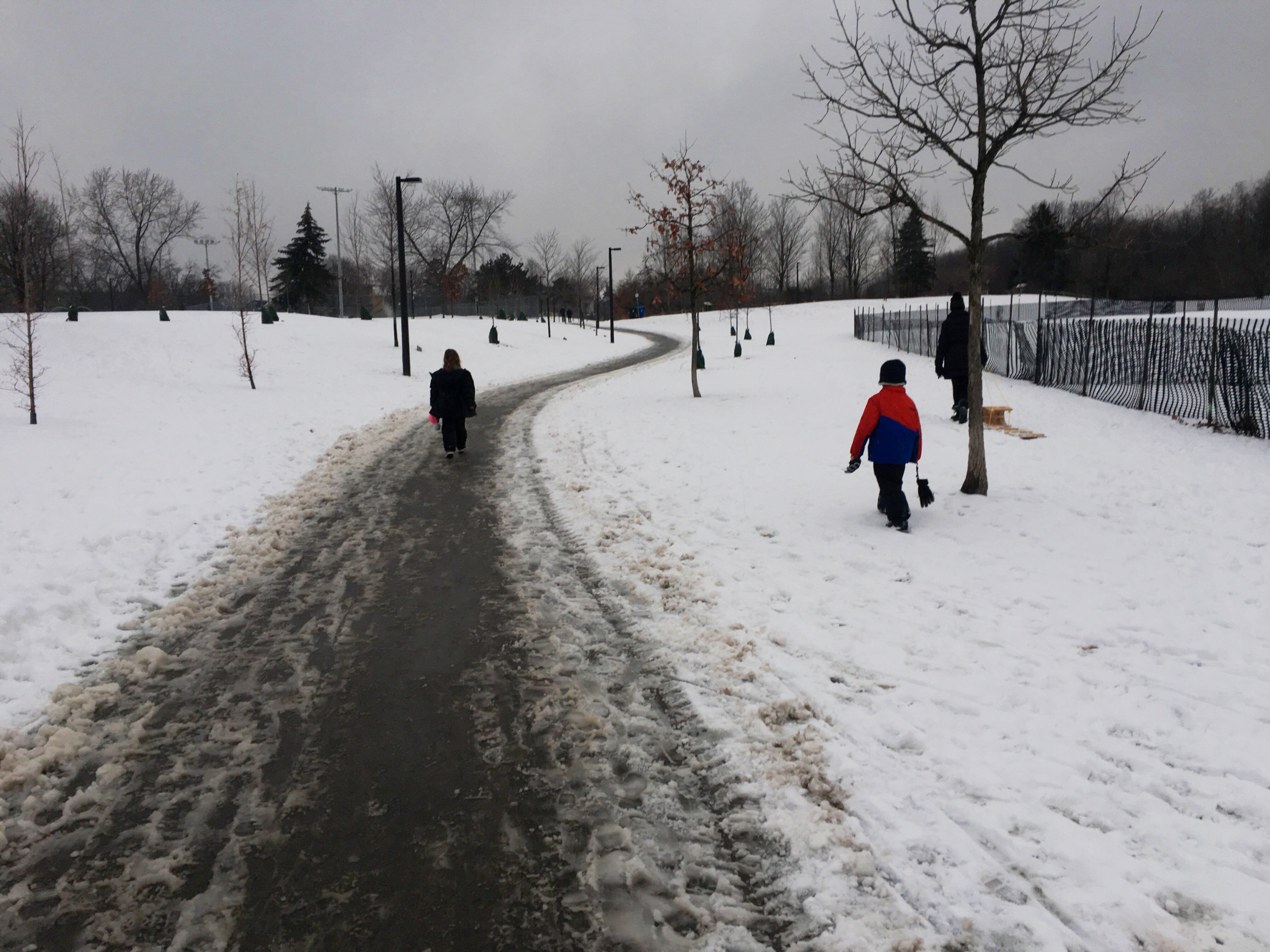 an adult and two children walking in cedarvale park, toronto