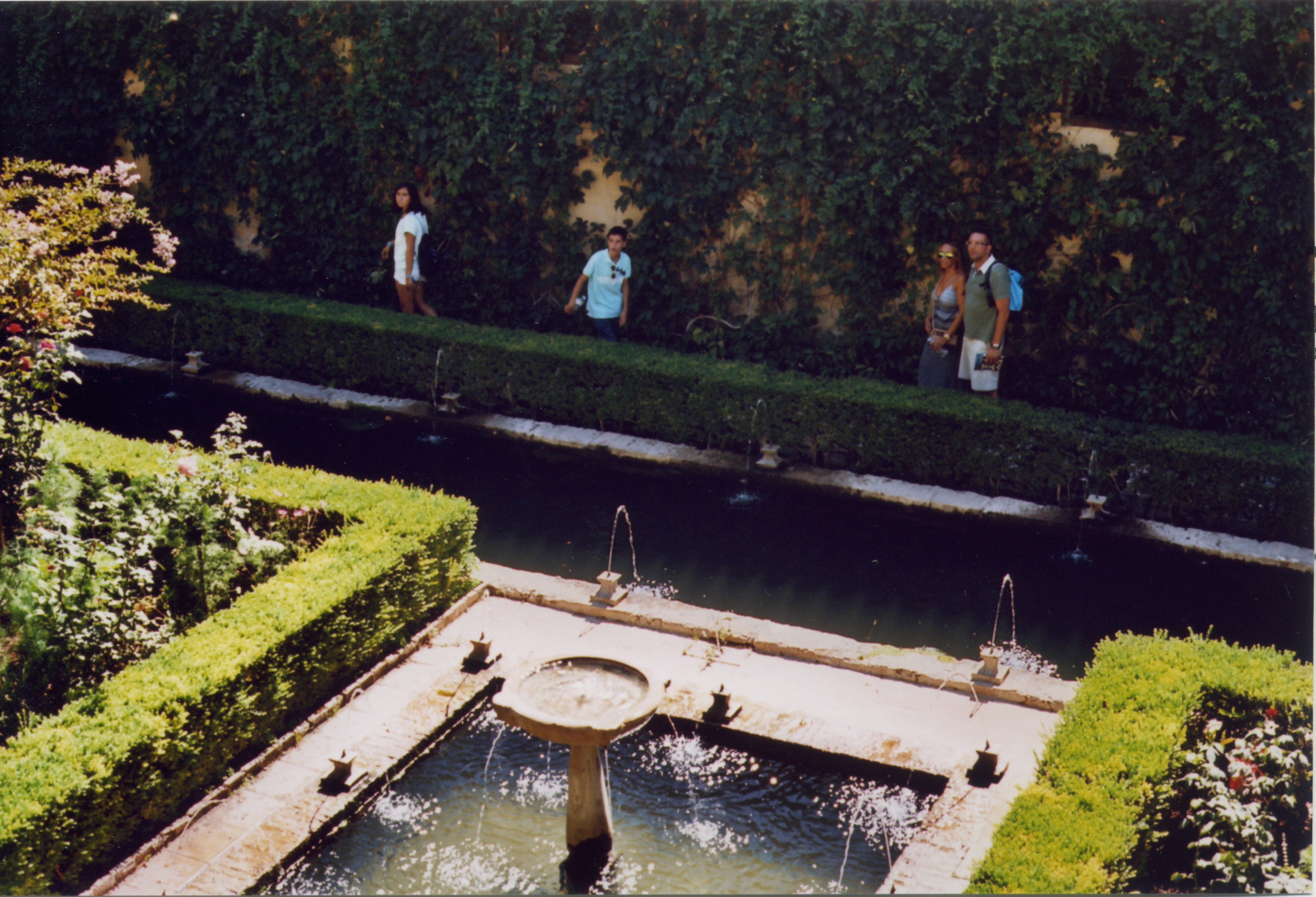 people standing by a fountain look up, at the alhambra, granada, spain