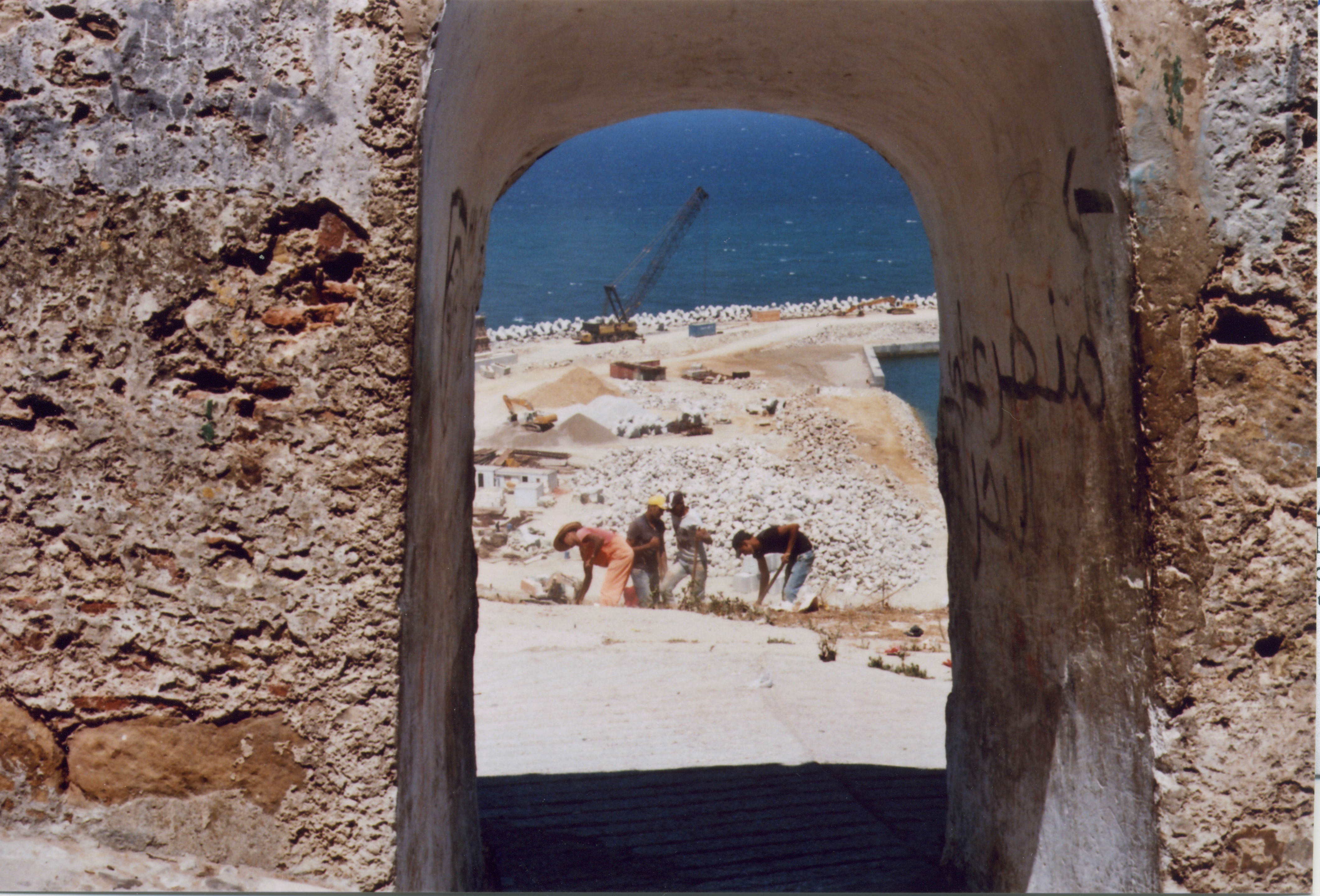 workers shovel dirt by the sea in tangiers, morocco