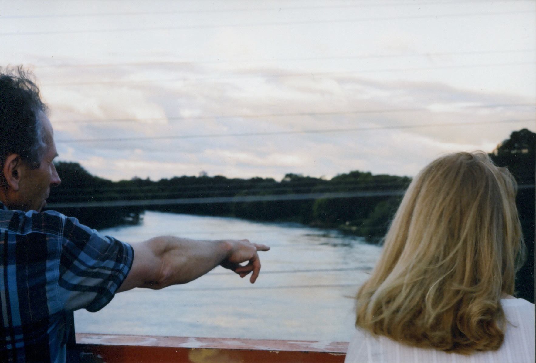 one person points and another person gazes over a river, winnipeg